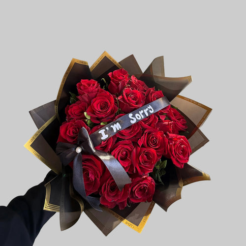 Bouquet of red roses with a black ribbon held by a person in a store.