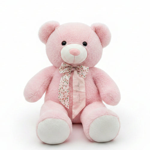 Pink teddy bear with a bow tie on a shelf in a store