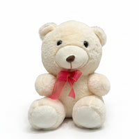 Small white teddy bear with a pink bow attached to a curtain.