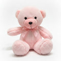 Pink teddy bear with a bow tie on a marble surface with a blurred background