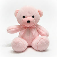 Pink teddy bear with a bow tie on a marble surface with a blurred background