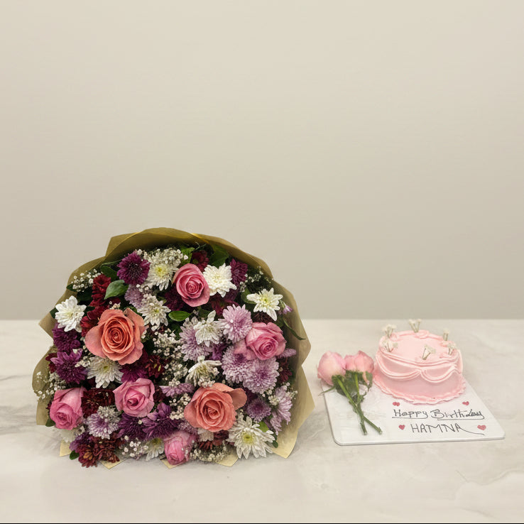 Bouquet of flowers and a small pink cake with a card on a counter, with fabric rolls and products in the background.