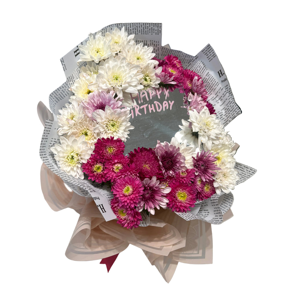 Bouquet of flowers with a 'Happy Birthday' card on a marble surface.