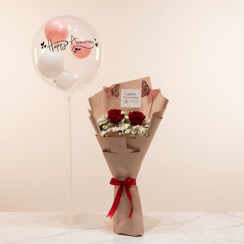 Bouquet of red roses with a decorative bow on a marble surface, with balloons and gift boxes in the background.