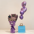 Bouquet of flowers, purple balloons, and a blue gift bag with 'LAYERS' branding on a table.