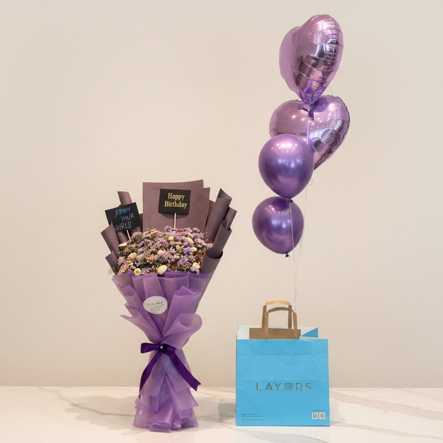 Bouquet of flowers, purple balloons, and a blue gift bag with 'LAYERS' branding on a table.