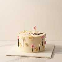 Decorative cake with floral designs and 'Eid Mubarak Amna' text on a patterned background.