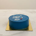 Small round blue cake with 'Happy Father's Day' text on a marble surface