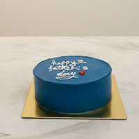 Small round blue cake with 'Happy Father's Day' text on a marble surface