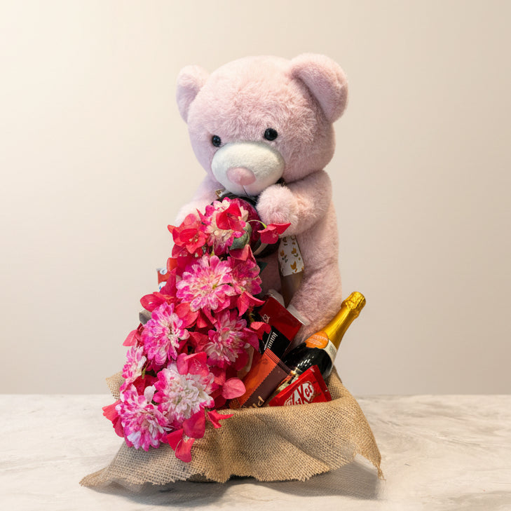 Pink teddy bear with a bouquet of flowers in front of a colorful fabric background