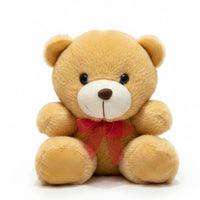 Plush teddy bear with a red bow tie on a marble surface with color swatches in the background.